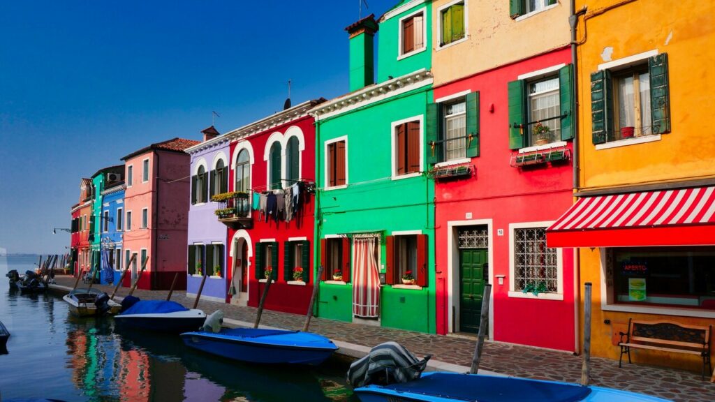 Vista de algumas casas italianas coloridas na beira das águas de Veneza.